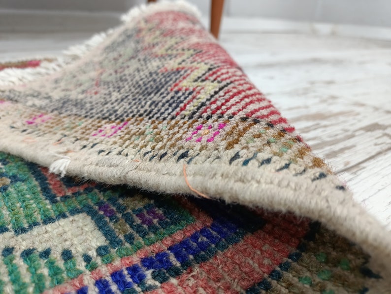Peut inclure: Gros plan sur un tapis tiss&eacute; multicolore avec une bordure &agrave; franges. Le tapis est pli&eacute;, r&eacute;v&eacute;lant l'envers du tissu.