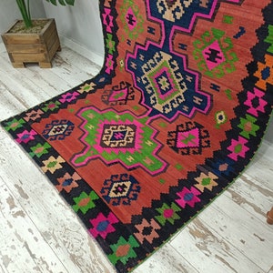 Puede incluir: Una alfombra colorida con un patr&oacute;n geom&eacute;trico en tonos rojos, rosas, verdes y negros. La alfombra tiene un dise&ntilde;o tradicional con detalles intrincados.