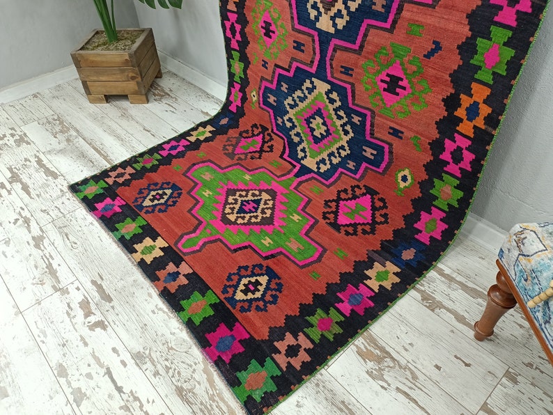 Puede incluir: Una alfombra colorida con un patr&oacute;n geom&eacute;trico en tonos rojos, rosas, verdes y negros. La alfombra tiene un dise&ntilde;o tradicional con detalles intrincados.