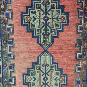 May include: A red runner rug with a geometric pattern in shades of blue, green, and pink. The rug has a fringed edge.