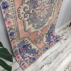 Pode incluir: Um tapete vintage rosa e azul com um padr&atilde;o floral. O tapete tem um aspeto desbotado e desgastado, perfeito para adicionar um toque de estilo bo&eacute;mio &agrave; sua casa.