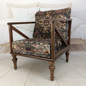 May include: A dark brown wooden armchair with a patterned fabric seat and back. The chair has a unique X-shaped design on the back and turned legs.