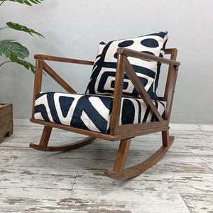 May include: A wooden rocking chair with a black and white geometric patterned cushion. The chair has a unique X-shaped design on the back.