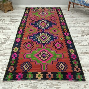 Puede incluir: Una alfombra colorida con un patr&oacute;n geom&eacute;trico en tonos de rosa, verde, azul y negro. La alfombra tiene un dise&ntilde;o tradicional con detalles intrincados.