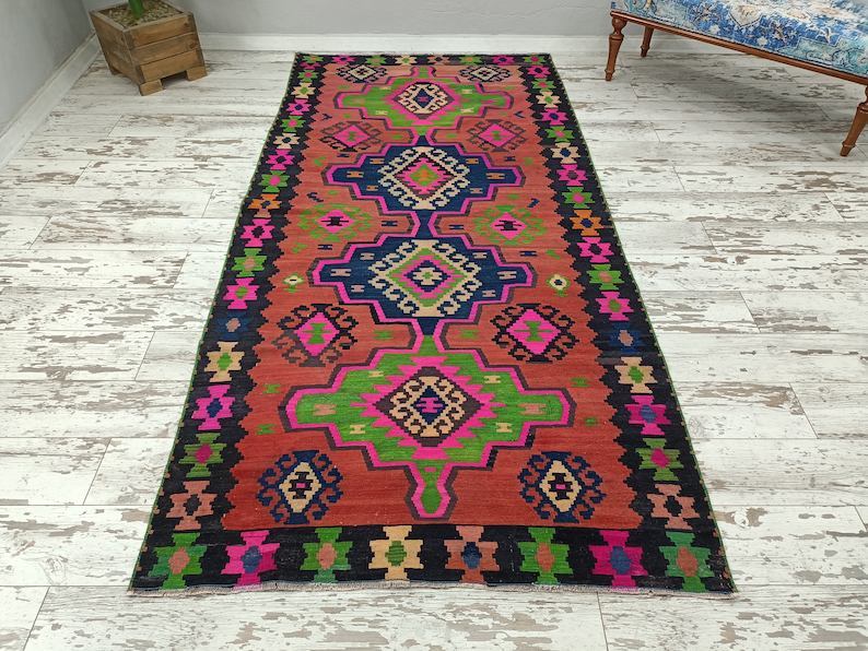 Puede incluir: Una alfombra colorida con un patr&oacute;n geom&eacute;trico en tonos de rosa, verde, azul y negro. La alfombra tiene un dise&ntilde;o tradicional con detalles intrincados.