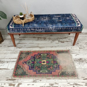 Peut inclure: Un banc bleu et blanc &agrave; motifs avec des pieds en bois est pos&eacute; sur un sol en bois blanchi &agrave; la chaux. Un petit tapis &agrave; motifs g&eacute;om&eacute;triques rose, vert et bleu se trouve devant le banc.