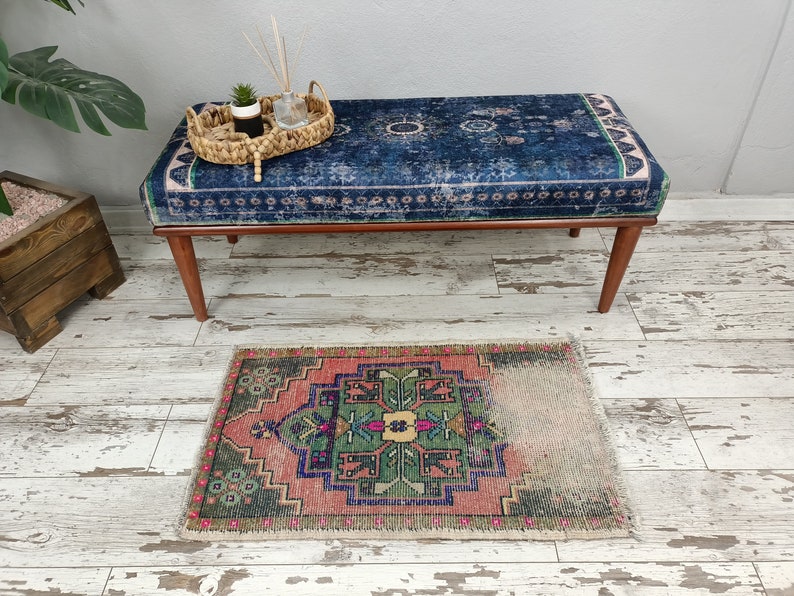 Peut inclure: Un banc bleu et blanc &agrave; motifs avec des pieds en bois est pos&eacute; sur un sol en bois blanchi &agrave; la chaux. Un petit tapis &agrave; motifs g&eacute;om&eacute;triques rose, vert et bleu se trouve devant le banc.