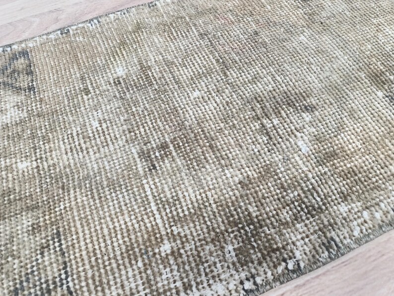 May include: A close-up of a beige and brown woven rug with a subtle pattern. The rug has a distressed, vintage look and is made of natural fibres.