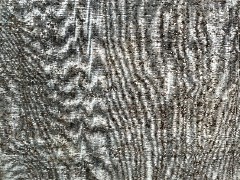 May include: Close-up of a textured, woven fabric with a gray and brown color scheme. The fabric has a subtle pattern and a slightly rough texture.