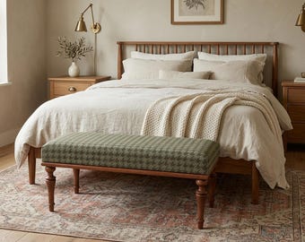 May include: A bedroom interior with a wooden bed, bedside tables, and a patterned bench. The bench has a green and white houndstooth design. A cream blanket is on the bed, and a rug with a faded pattern is on the floor. The room has a neutral color palette.