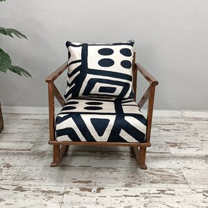 May include: A rocking chair with a black and white geometric patterned cushion. The chair is made of wood and has a dark brown finish.