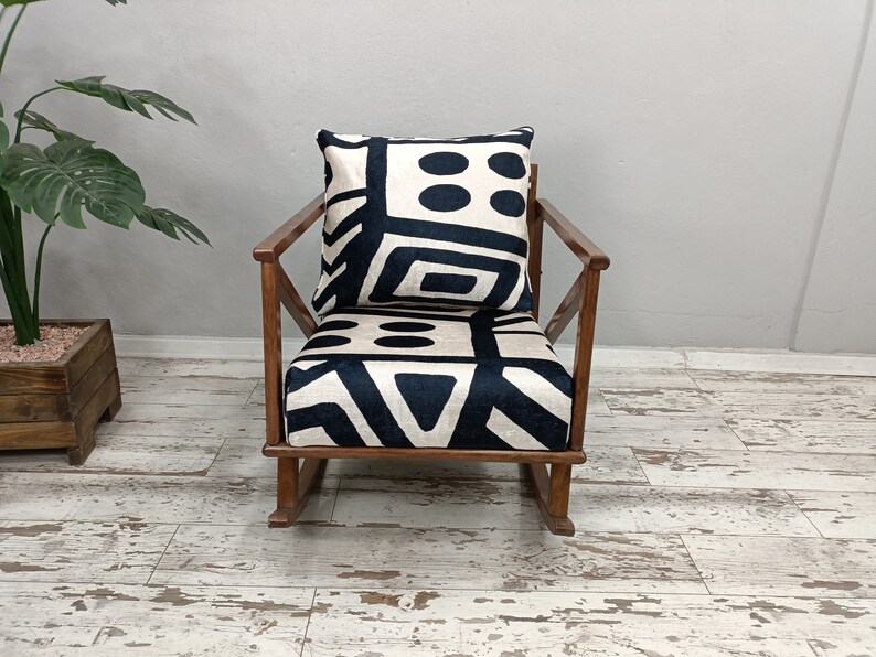 May include: A rocking chair with a black and white geometric patterned cushion. The chair is made of wood and has a dark brown finish.