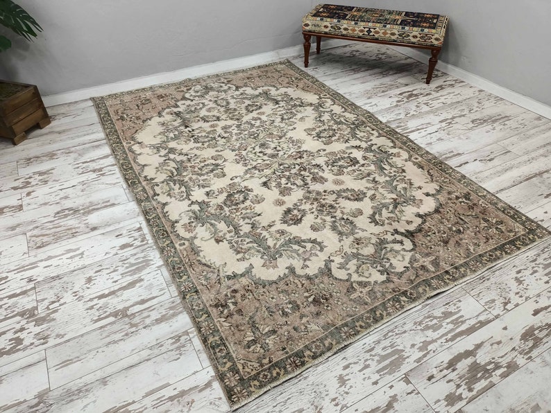 May include: A vintage cream-coloured rug with a floral pattern in shades of brown and green. The rug has a distressed look and is perfect for adding a touch of vintage charm to any room.