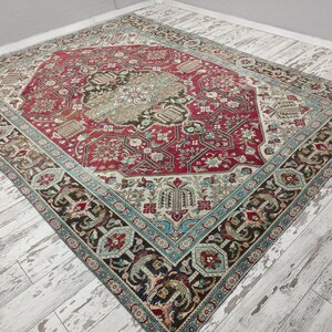 May include: A vintage rug with a red, blue, and cream color scheme. The rug has a central medallion with intricate floral patterns and a border with geometric designs.