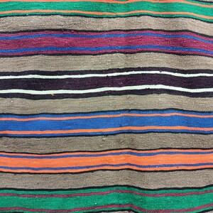 May include: A woven rug with horizontal stripes in shades of green, brown, red, blue, and orange.