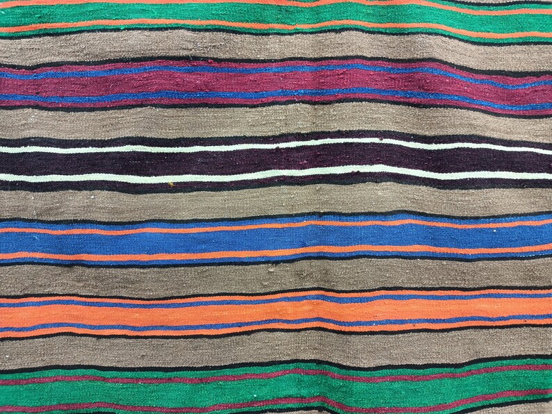 May include: A woven rug with horizontal stripes in shades of green, brown, red, blue, and orange.