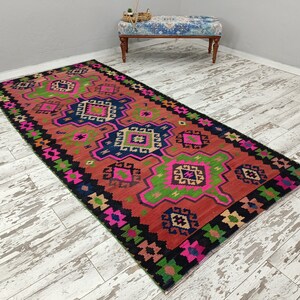 Puede incluir: Una alfombra colorida con un patr&oacute;n geom&eacute;trico en tonos de rosa, verde, azul y negro. La alfombra tiene un dise&ntilde;o tradicional con detalles intrincados.