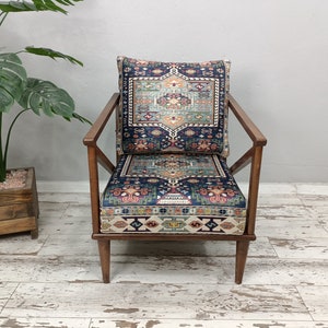 Puede incluir: Un sill&oacute;n de madera con un marco de madera oscura y un coj&iacute;n estampado. El coj&iacute;n es de color azul oscuro con un dise&ntilde;o geom&eacute;trico colorido. El sill&oacute;n est&aacute; sobre un suelo de madera blanca.