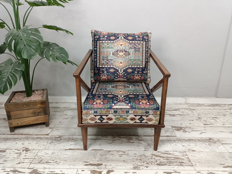 Puede incluir: Un sill&oacute;n de madera con un marco de madera oscura y un coj&iacute;n estampado. El coj&iacute;n es de color azul oscuro con un dise&ntilde;o geom&eacute;trico colorido. El sill&oacute;n est&aacute; sobre un suelo de madera blanca.