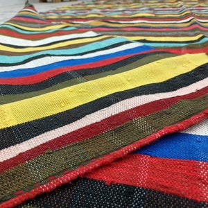 May include: A colorful striped woven rug with a variety of colors including red, yellow, blue, green, and black.