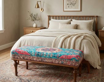 May include: A bedroom scene featuring a wooden bed frame, nightstands, and a patterned rug. A bench with a turquoise and red patterned top sits at the foot of the bed. The room has a neutral color palette with a warm, inviting atmosphere.