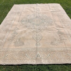 May include: A large, off-white rug with a detailed, intricate pattern in a lighter shade of gray. The rug has a faded, vintage look and features a central medallion design.