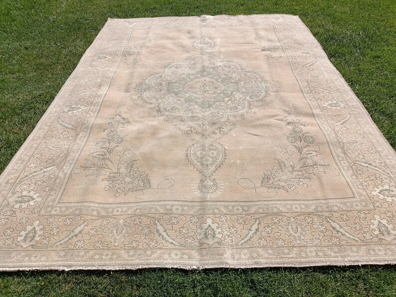 May include: A large, off-white rug with a detailed, intricate pattern in a lighter shade of gray. The rug has a faded, vintage look and features a central medallion design.