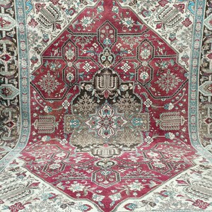 May include: A vintage Persian rug with a red, cream, and blue floral pattern. The rug has a central medallion and a border with intricate designs.