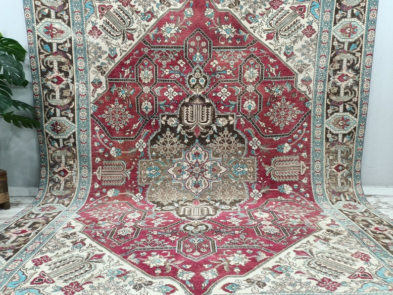 May include: A vintage Persian rug with a red, cream, and blue floral pattern. The rug has a central medallion and a border with intricate designs.
