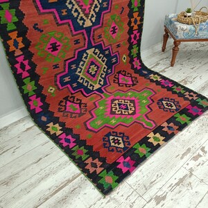 Puede incluir: Una alfombra colorida con un patr&oacute;n geom&eacute;trico en tonos de rojo, rosa, verde, azul y negro. La alfombra tiene un dise&ntilde;o turco tradicional.