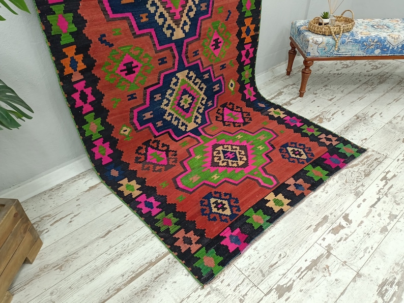 Puede incluir: Una alfombra colorida con un patr&oacute;n geom&eacute;trico en tonos de rojo, rosa, verde, azul y negro. La alfombra tiene un dise&ntilde;o turco tradicional.