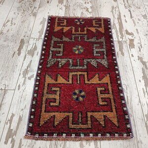 May include: A red, orange, and blue patterned runner rug with a geometric design. The rug has a fringe border.