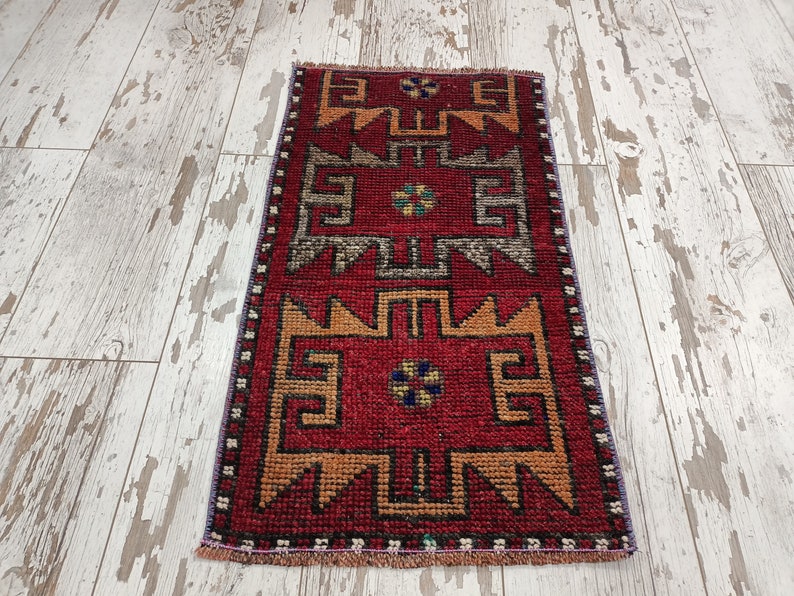 May include: A red, orange, and blue patterned runner rug with a geometric design. The rug has a fringe border.