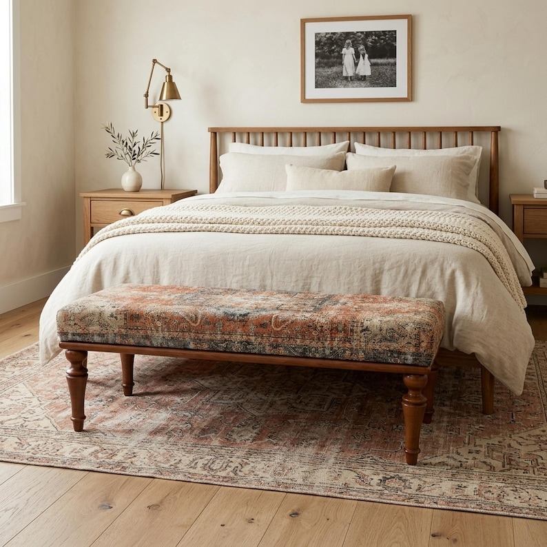 a cozy bedroom with a large bed, a wooden headboard, and a patterned bench. The room has a warm, inviting atmosphere with a wooden floor and a rug.