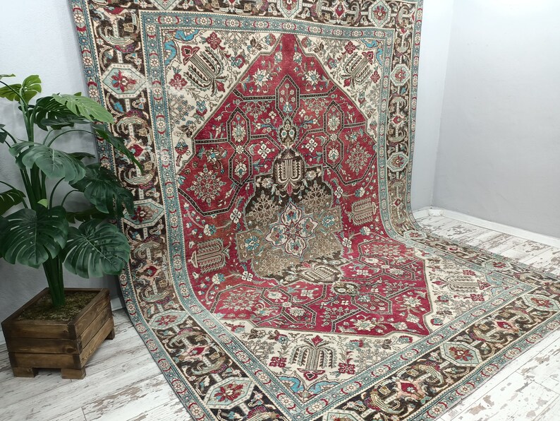 May include: A large, intricately patterned rug with a red, cream, and blue color scheme. The rug has a central medallion with a floral design and a border with geometric patterns.