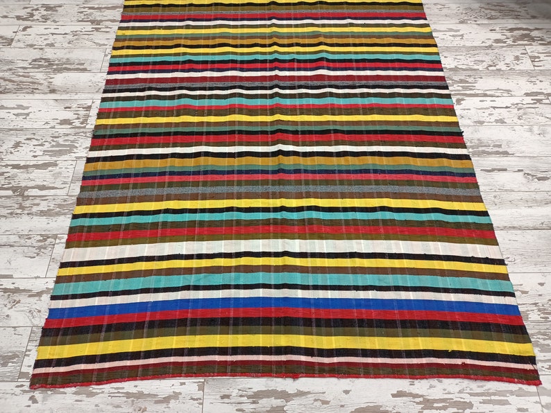 May include: Multicolored striped throw blanket with a variety of colors including red, yellow, blue, green, and brown.