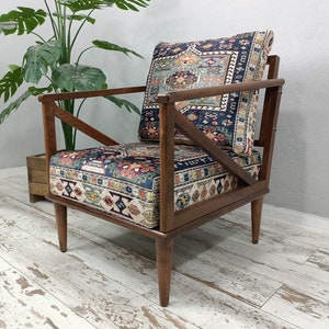 Puede incluir: Un sill&oacute;n de madera con un coj&iacute;n de tela estampado. El coj&iacute;n presenta un dise&ntilde;o geom&eacute;trico colorido en tonos azules, rojos y verdes. La silla tiene un marco y patas de madera oscura.