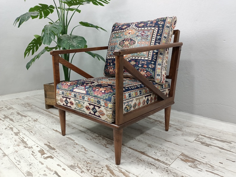 Puede incluir: Un sill&oacute;n de madera con un coj&iacute;n de tela estampado. El coj&iacute;n presenta un dise&ntilde;o geom&eacute;trico colorido en tonos azules, rojos y verdes. La silla tiene un marco y patas de madera oscura.