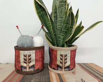 May include: Two fabric storage baskets with a geometric pattern. One basket holds two balls of yarn and knitting needles. The other basket holds a potted snake plant.