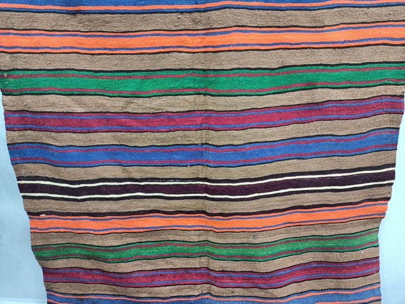 May include: A striped woven rug with alternating bands of brown, orange, green, blue, red, and black.