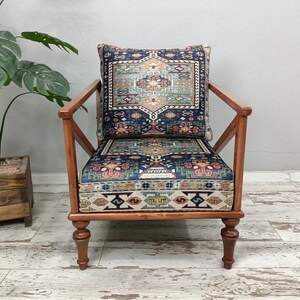 Puede incluir: Un sill&oacute;n de madera con un coj&iacute;n estampado en azul oscuro y rojo y un coj&iacute;n de respaldo a juego. El sill&oacute;n tiene un dise&ntilde;o simple y moderno con un respaldo ligeramente inclinado y un asiento amplio.