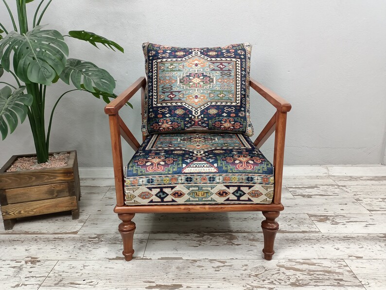 Puede incluir: Un sill&oacute;n de madera con un coj&iacute;n estampado en azul oscuro y rojo y un coj&iacute;n de respaldo a juego. El sill&oacute;n tiene un dise&ntilde;o simple y moderno con un respaldo ligeramente inclinado y un asiento amplio.