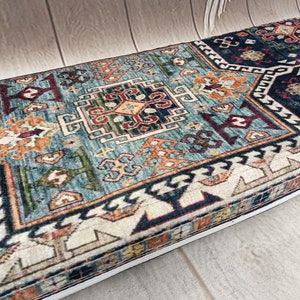 Pu&ograve; includere: Un tappeto rettangolare blu, bianco, rosso e arancione con un bordo bianco. Il tappeto ha un design tradizionale con dettagli intricati.