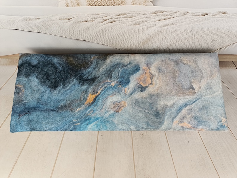 Puede incluir: Un coj&iacute;n de tiro azul y gris con un patr&oacute;n abstracto y un sutil brillo dorado.