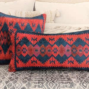 Könnte beinhalten: Zwei dekorative Kissen mit einem roten und blauen geometrischen Muster. Die Kissen sind aus einem weichen, gewebten Stoff gefertigt und haben ein traditionelles Design.