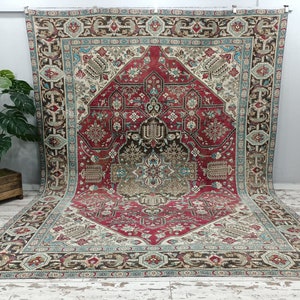 May include: A vintage rug with a red, cream, and brown color scheme. The rug features a central medallion with intricate floral and geometric patterns. The rug has a faded, worn look, adding to its antique charm.
