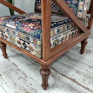 Puede incluir: Un sill&oacute;n de madera con un asiento y respaldo de tela estampada. La silla tiene un acabado marr&oacute;n oscuro y patas torneadas.