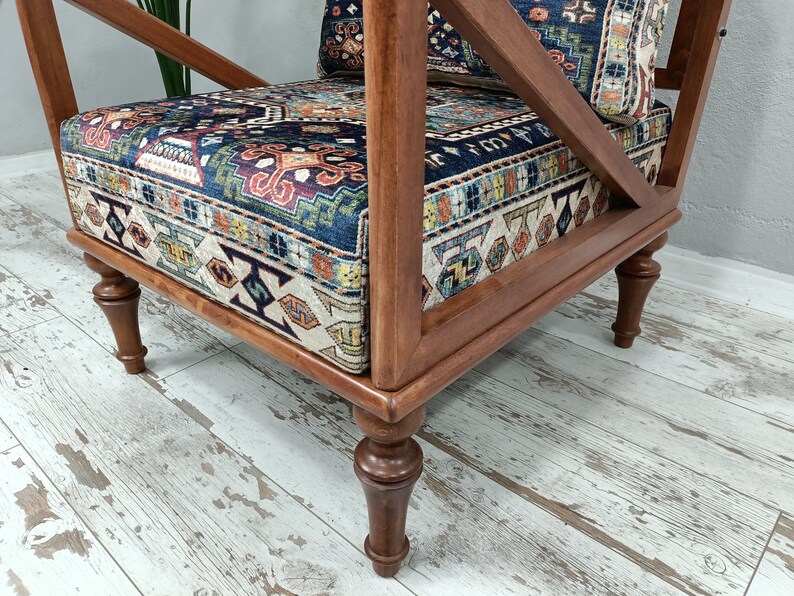 Puede incluir: Un sill&oacute;n de madera con un asiento y respaldo de tela estampada. La silla tiene un acabado marr&oacute;n oscuro y patas torneadas.