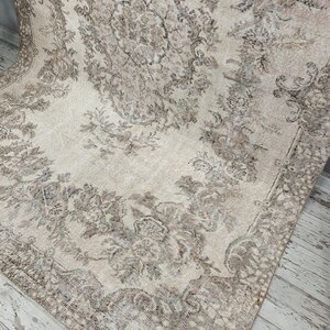 May include: A vintage rug with a cream background and a floral pattern in shades of brown. The rug has a distressed look and is perfect for adding a touch of vintage charm to any room.