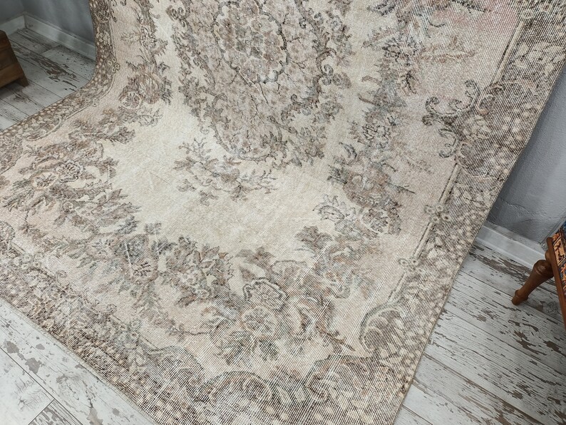 May include: A vintage rug with a cream background and a floral pattern in shades of brown. The rug has a distressed look and is perfect for adding a touch of vintage charm to any room.